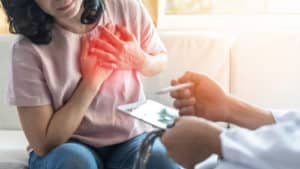 woman patient with doctor examing heart pain